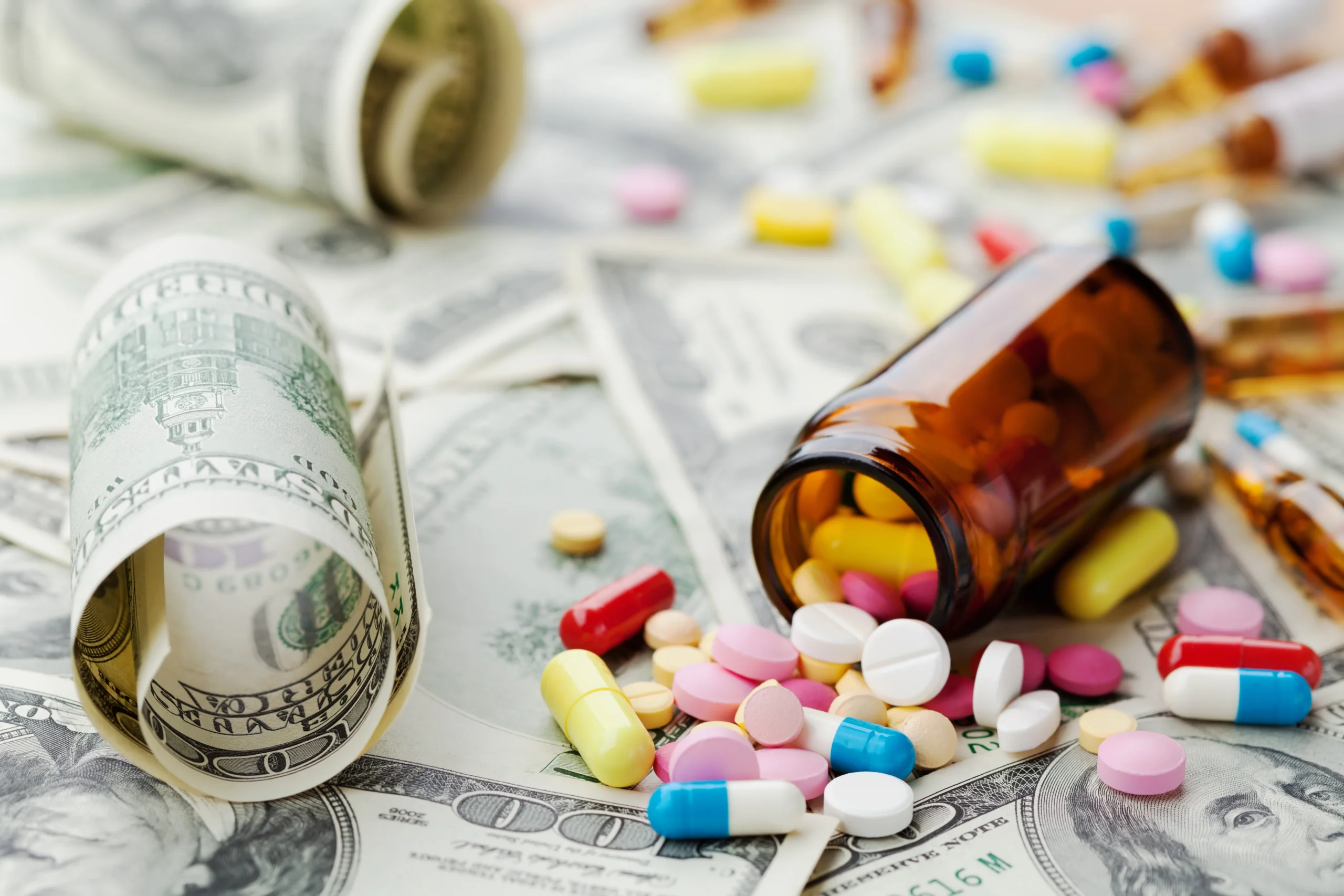 bottle of pills spilled on top of 100 dollar bills
