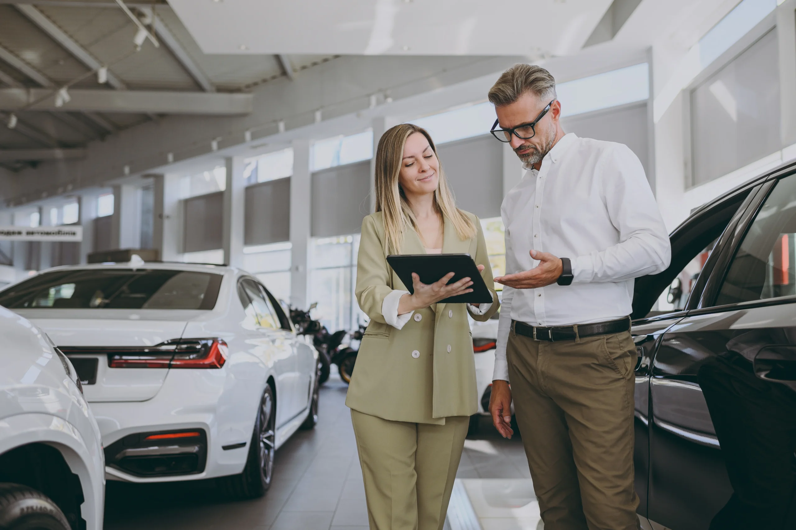 inside of a car dealership where a representative is showing a man paperwork